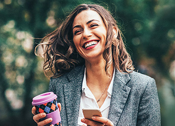 Businesswoman outside with coffee and using mobile device