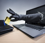 Gloved hand coming through laptop screen to steal credit card.