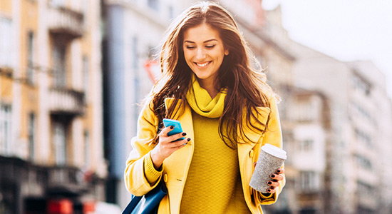 Young woman walking in city looking at cell phone