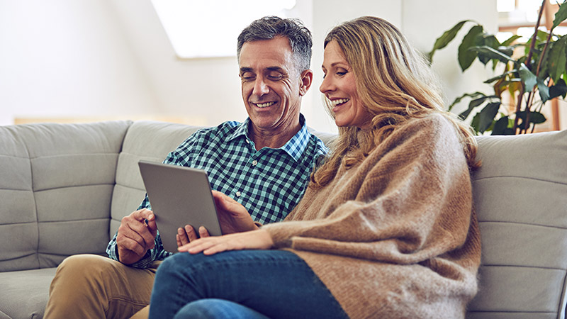 Happy couple on couch with tablet.