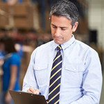 Business owner reviewing document in industrial plant.